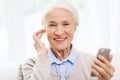 Senior woman with smartphone and earphones at home Royalty Free Stock Photo