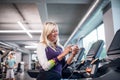 A senior woman with smartphone in gym doing cardio work out exercise. Royalty Free Stock Photo