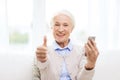 Senior woman with smartphone showing thumbs up