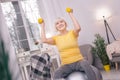 Senior woman smiling and exercising with dumbbells on yoga ball