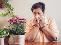 Senior woman sneezing in front of flower pot.Allergy from flowers , health and medication concept Royalty Free Stock Photo