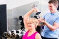 Senior woman at sport exercise in gym with trainer Royalty Free Stock Photo