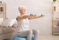 Senior woman in sportswear exercising with dumbbells at home Royalty Free Stock Photo