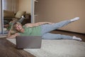 Senior woman in sportswear watching online video on laptop and doing fitness exercises at home Royalty Free Stock Photo