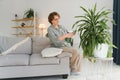 Senior woman sprays plants in flowerpots. Happy female caring for house plant. Mature Woman taking care of plants at her Royalty Free Stock Photo