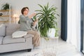 Senior woman sprays plants in flowerpots. Happy female caring for house plant. Mature Woman taking care of plants at her Royalty Free Stock Photo