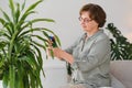 Senior woman sprays plants in flowerpots. Happy female caring for house plant. Mature Woman taking care of plants at her Royalty Free Stock Photo