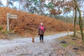 Senior woman standing next to her dog at a path intersection Royalty Free Stock Photo