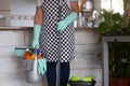 Senior woman standing and ready to start with the housework. Close to she a plastic bucket with items for cleaning. One alone