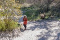 Senior woman standing on a sandy path surrounded by vegetation, with her mobile phone gimbal tripod head stabilizer in hand