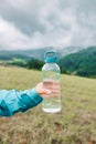 caucasian 50s blonde girl drinking water from plastic bottle. Mountain background