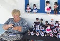 Senior woman at the street of Nazare making selling traditional handmade dolls, Portugal