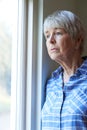 Senior Woman Suffering From Depression Looking Out Of Window