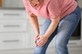 Senior woman suffering from knee pain in kitchen, closeup. Royalty Free Stock Photo