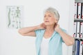 Senior woman suffering from neck pain in medical office Royalty Free Stock Photo