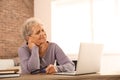 Senior woman suffering from neck pain while sitting at table with laptop Royalty Free Stock Photo