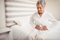 Senior woman suffering from stomach ache sitting on bed Royalty Free Stock Photo