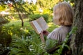 Senior woman in summer garden reading a book sitting near a tree Royalty Free Stock Photo