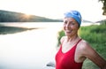 Senior woman in swimsuit standing by lake outdoors before swimming. Royalty Free Stock Photo