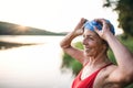 Senior woman in swimsuit standing by lake outdoors before swimming. Royalty Free Stock Photo
