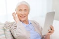 Senior woman with tablet pc and earphones at home Royalty Free Stock Photo