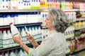 Senior woman taking picture of milk bottle Royalty Free Stock Photo