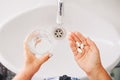 Senior woman taking pills. Women drinking prescription drugs, holding glass of water. drug treatment. top view of hands