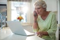 Senior woman talking on mobile phone while using laptop Royalty Free Stock Photo