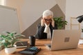 Senior woman touching temples experiencing stress in office. Mature lady tired of working feeling headache sick rubbing Royalty Free Stock Photo