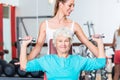 Senior woman with trainer in gym lifting dumbbell Royalty Free Stock Photo