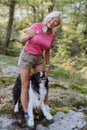 Senior woman training her dog during walk in forest. Royalty Free Stock Photo