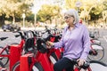 senior woman unlocking rental bike with mobile app