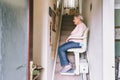 Senior woman using automatic stair lift on a staircase at her home. Medical Stairlift for disabled people and elderly