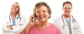 Senior Woman Using Cell Phone and Doctors Behind Royalty Free Stock Photo