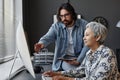 Senior woman using computer in class with male teacher helping Royalty Free Stock Photo