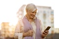 Senior woman using mobile phone outdoors in autumn Royalty Free Stock Photo