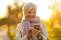 Senior woman using mobile phone outdoors in autumn Royalty Free Stock Photo