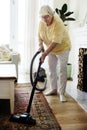 Senior woman vacuuming a carpet