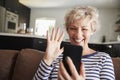 Senior woman video calling on smartphone at home, close up