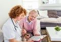 Senior woman is visited by her doctor or caregiver. Female doctor or nurse talking with senior patient. Medicine, age, health care Royalty Free Stock Photo