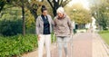 Senior woman, walker and nurse outdoor in a park with healthcare for elderly exercise. Walking, healthcare professional