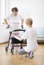 Senior woman with walker trying to walk again and helpful physiotherapist supporting her