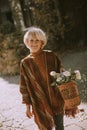 Senior woman walking with basket full of flowers and groceries in autumn park Royalty Free Stock Photo