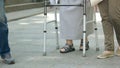 Senior woman walking with metal walker outdoors.