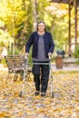 Senior woman walking outdoors with walker in autumn park