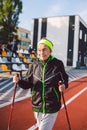 Senior woman walking with walking poles in stadium on a red rubber cover. Elderly woman 88 years old doing Nordic walking Royalty Free Stock Photo