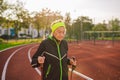 Senior woman walking with walking poles in stadium on a red rubber cover. Elderly woman 88 years old doing Nordic walking Royalty Free Stock Photo