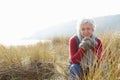 Senior Woman Walking Through Sand Dunes On Winter Beach