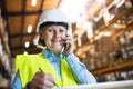 Senior woman warehouse manager or supervisor with smartphone, making phone call. Royalty Free Stock Photo