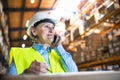 Senior woman warehouse manager or supervisor with smartphone, making phone call. Royalty Free Stock Photo